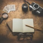 flat ray photography of book, pencil, camera, and with lens